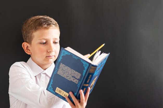 Student child at the blackboard with a book