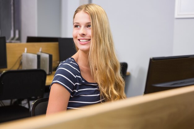 Foto student die aan computer in klaslokaal werkt