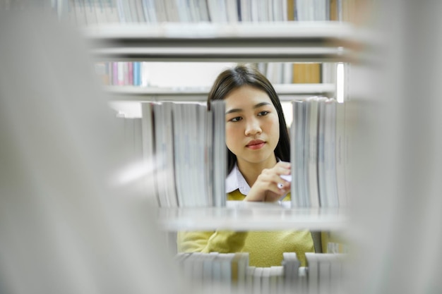 Student die boek kiest en leest in de bibliotheek