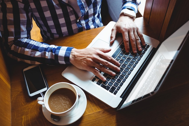 Student die laptop met behulp van terwijl het hebben van koffie