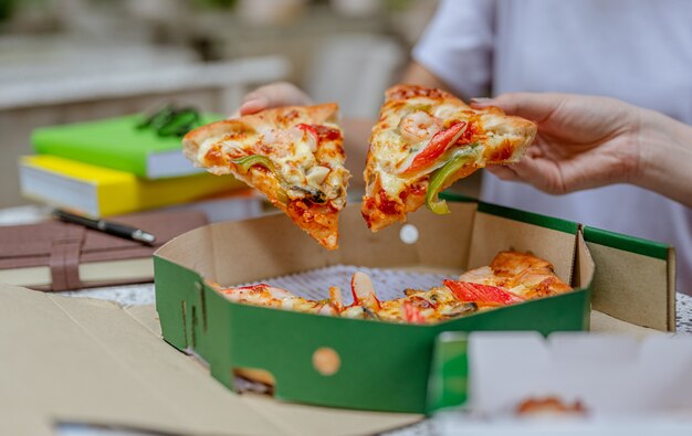 Student die pizza eet terwijl hij bijles geeft en aan een project werkt Universiteiten Kennisboek