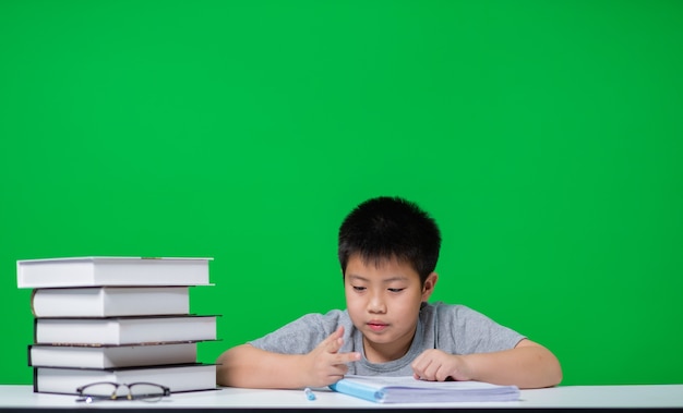 Student doing homework on green screen, child writing paper, education concept, back to school