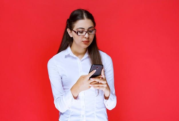 Student in eyeglasses chatting at her smartphone.