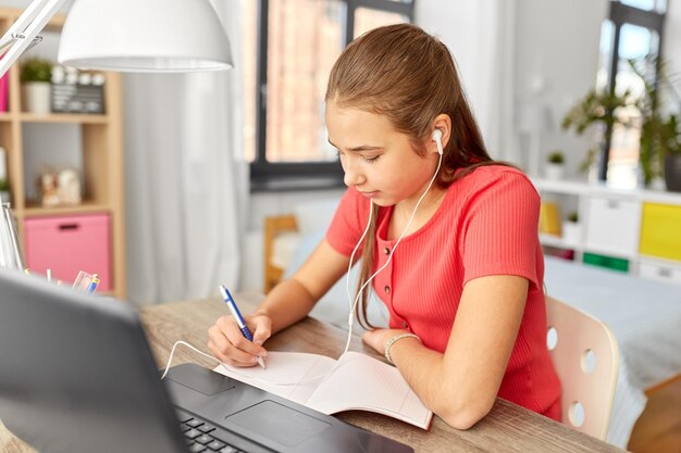 student girl in earphones learning at home