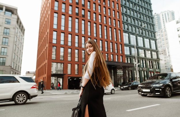 Foto studentessa in abiti formali si trova sulla strada di una metropoli