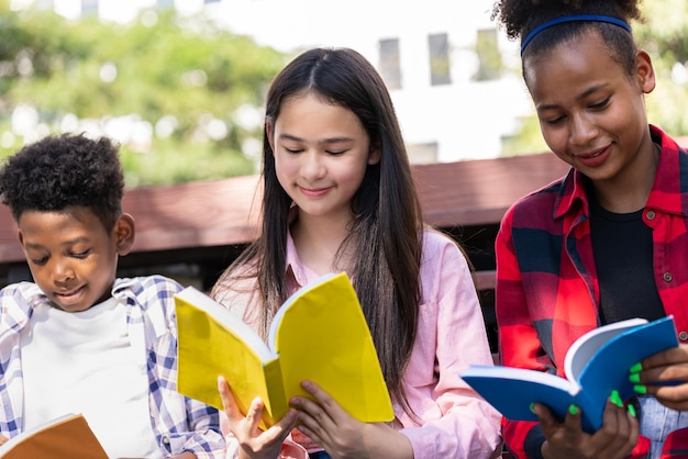 学校の公園で友達と本を読んでいる学生の女の子