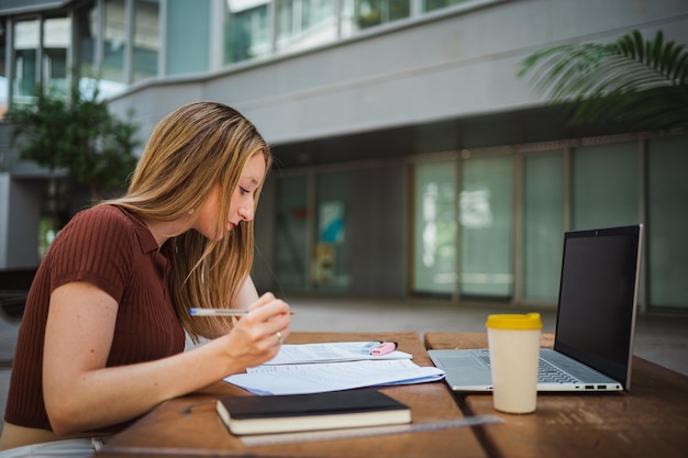 Student girl reviewing her notes for the exam she seems focus\
and she is at the uni campus