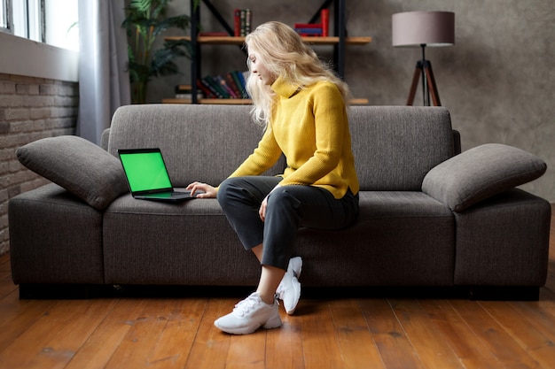 student girl sit on sofa holding laptop looking at mock up screen