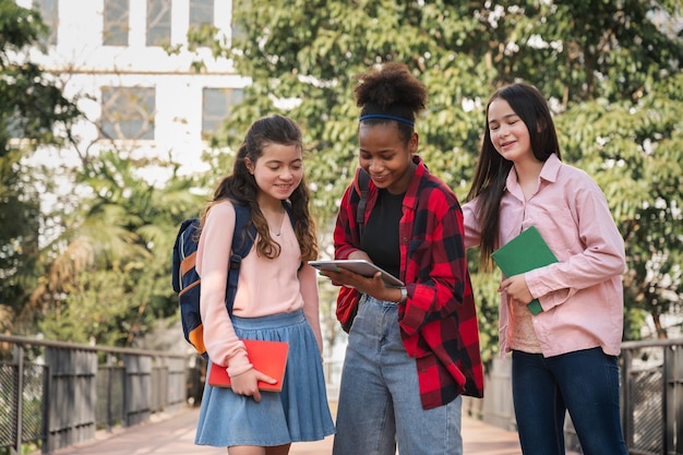 学生の女の子は友達とタブレットを使用して学校の公園でタブレットを見て