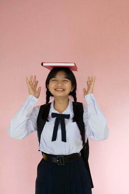 Student girl with backpack and pink book on pink background