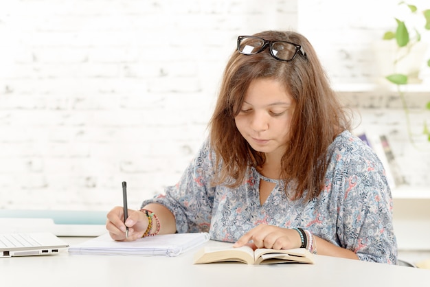 Photo student girl, with eyeglasses, does homework