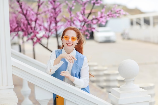 A student girl with a good mood goes near the building with stone steps