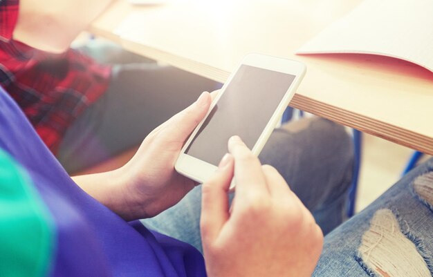 写真 スマートフォンでテキストメッセージを送る学生の女の子