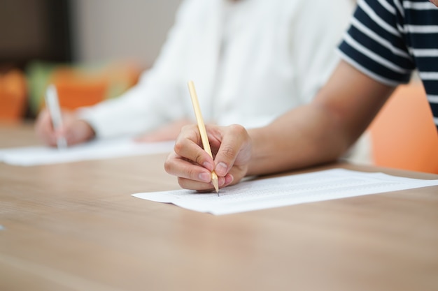  student hand using pencil for doing text exam