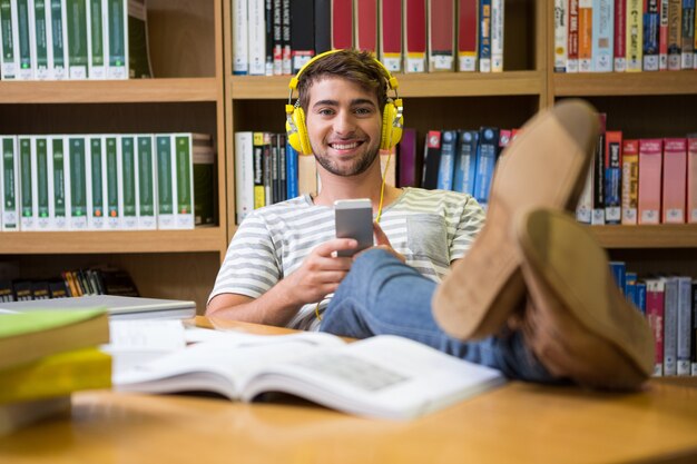 Student het luisteren muziek in de bibliotheek met smartphone