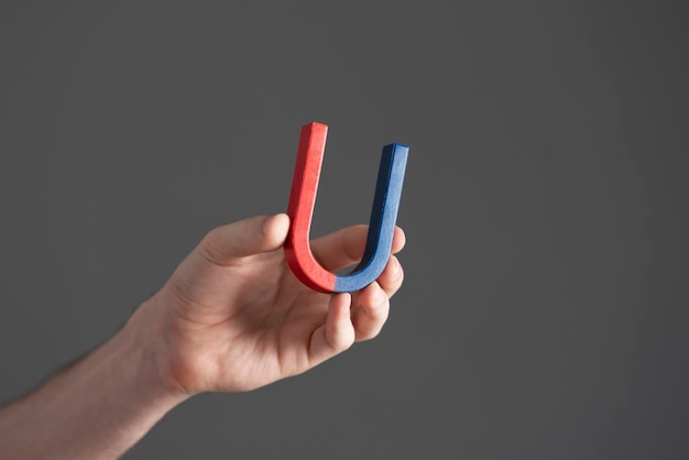 A student holding a blue and red magnet in shape of horseshoe making science tests