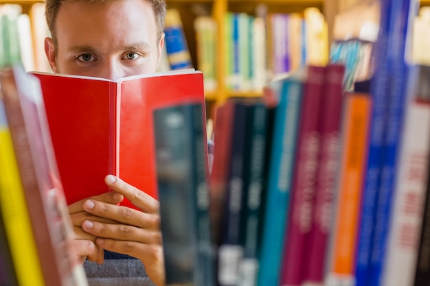 Student holding book in front of his face in the library