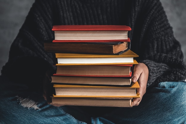 Studente che tiene in mano una pila di vecchi libri.