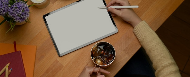 A student holding iced coffee mug while doing an assignment