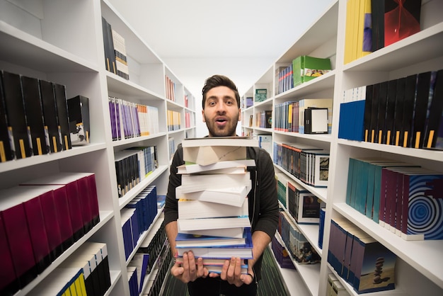 Student holding lot of books in school library Hard worker and persistence concept