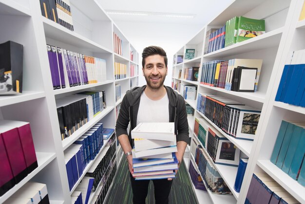 Student holding lot of books in school library Hard worker and persistence concept