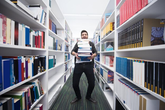 Student holding lot of books in school library hard worker and persistence concept