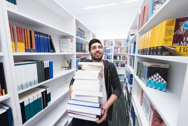 Student holding lot of books in school library Hard worker and persistence concept