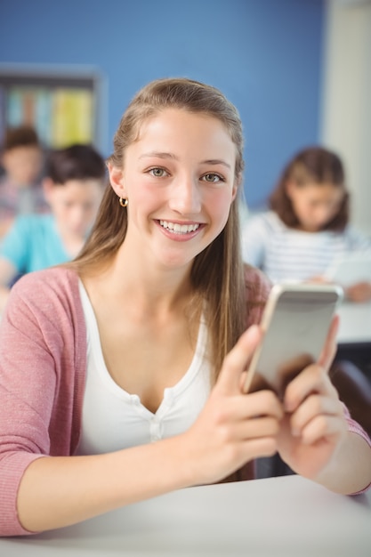 Student holding mobile phone in classroom