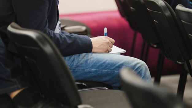 Student in auditorium schrijft in notitieblok met pen