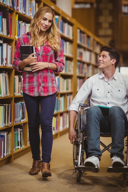 Student in rolstoel praten met klasgenoot in de bibliotheek