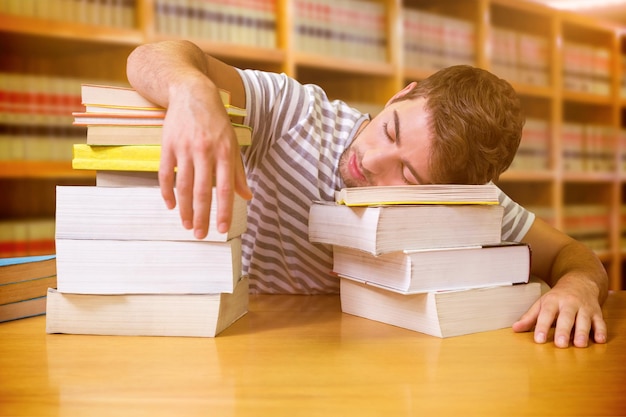 Student in slaap in de bibliotheek tegen close-up van een boekenplank