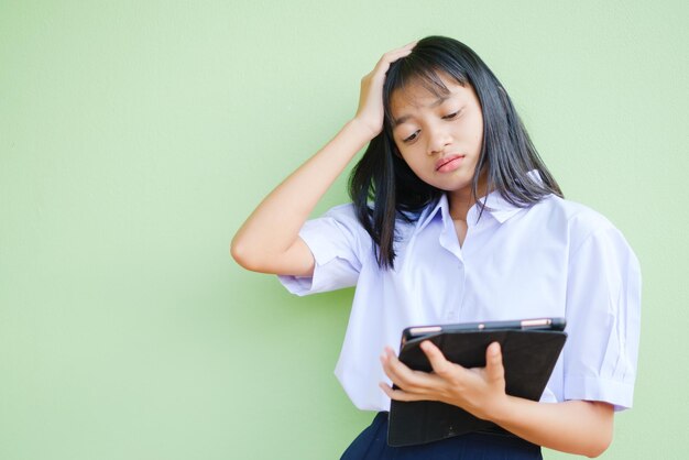 Student jong meisje houdt laptop blik hoofdpijn op groene achtergrond.