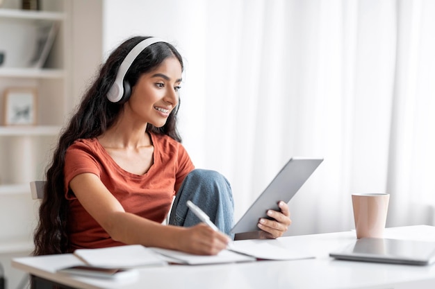 Student jonge indiase vrouw met behulp van digitale tablet-hoofdtelefoons