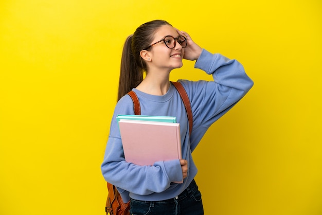 たくさん笑って孤立した黄色の背景の上の学生の子供の女性