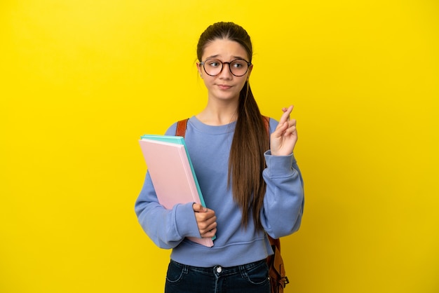 Student kid woman over isolated yellow background with fingers crossing and wishing the best