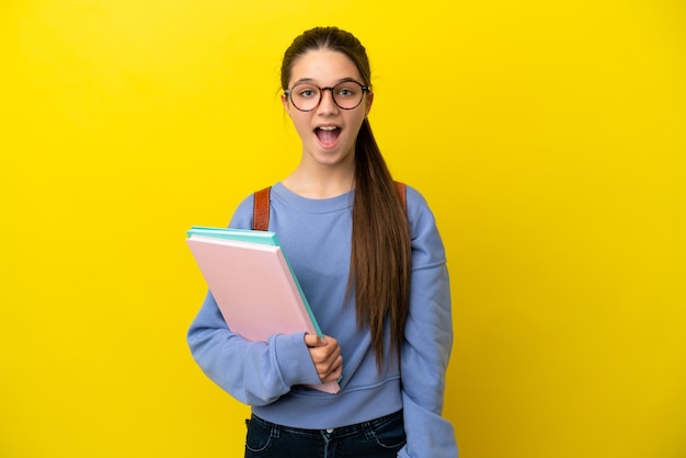 驚きの表情で孤立した黄色の背景上の学生の子供の女性