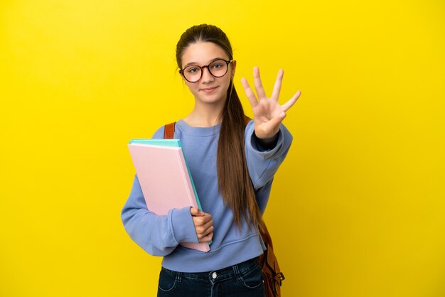 Student kind vrouw over geïsoleerde gele achtergrond gelukkig en vier tellen met vingers