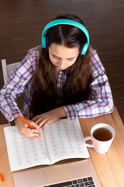 Student laptop making note, listening music headphones and reading book, drink coffee. Elearning concept.