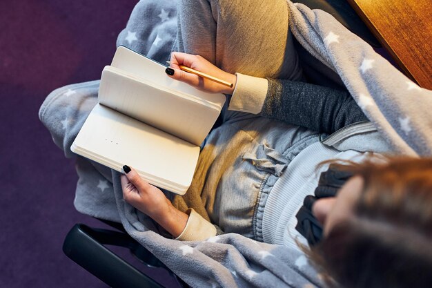 Foto studente che impara a casa, giovane donna che prende appunti, legge e impara da un libro