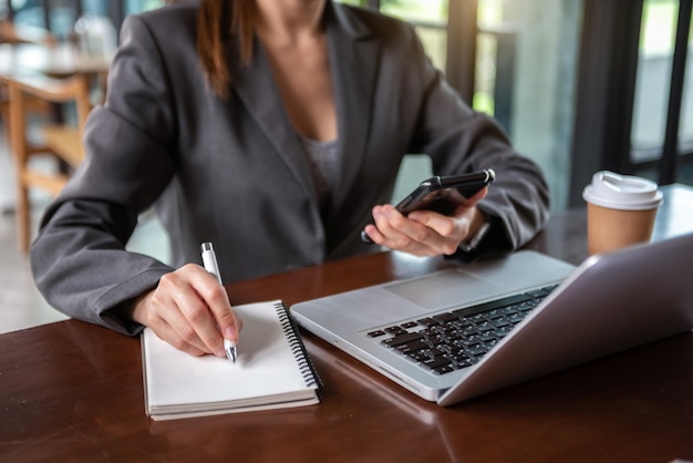 Studente che impara la lezione online utilizzando un computer portatile e scrivendo un taccuino sul posto di lavoro e il concetto di lavoro online in ufficio