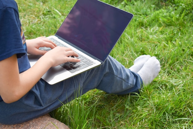 Студент учится в саду на компьютере.