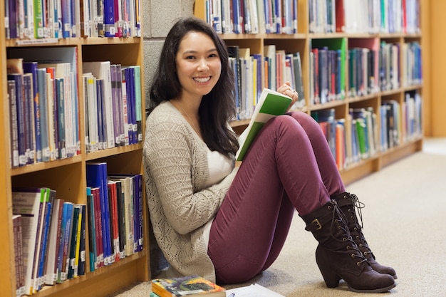 Student in a library leaning against a shelf