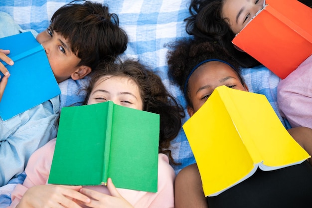 Student lie down holding book on face with friend at school park