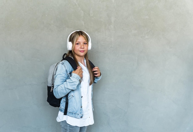 Student life modern lifestyle and education concept cheerful pretty female student with headphones and backpack