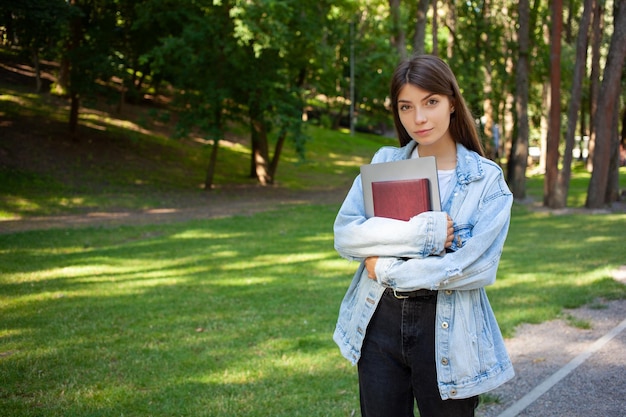 Student lifestyle concept Portret jong meisje met notitieblok en laptop dragen van casual kleding wandelen in het stadspark op een zomerdag Copy space