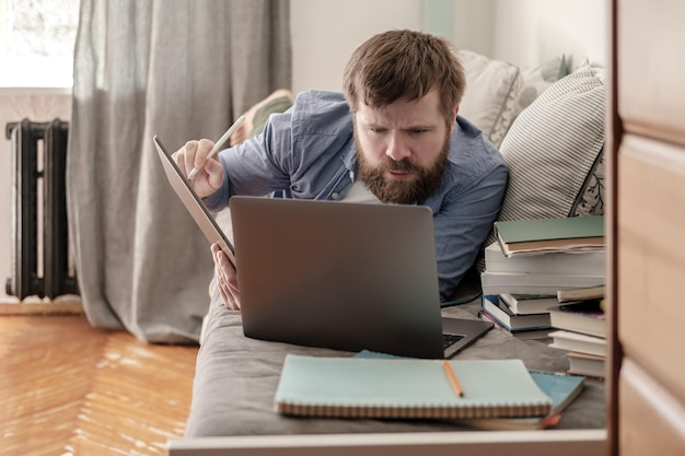 Student ligt op een bank en kijkt aandachtig naar een laptop. Concept van online onderwijs op afstand