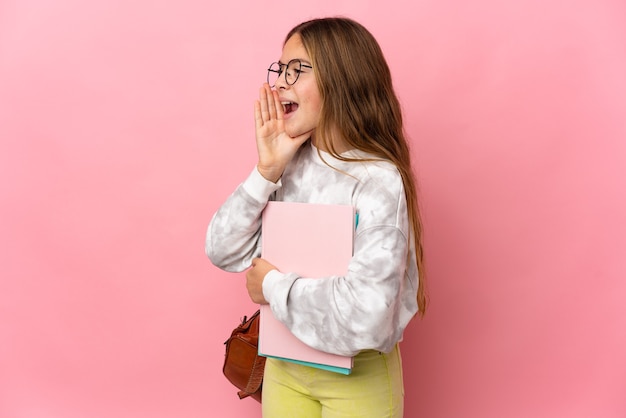 Student little girl over isolated pink background shouting with mouth wide open to the side