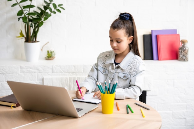 Student little school girl homework on laptop computer silver background