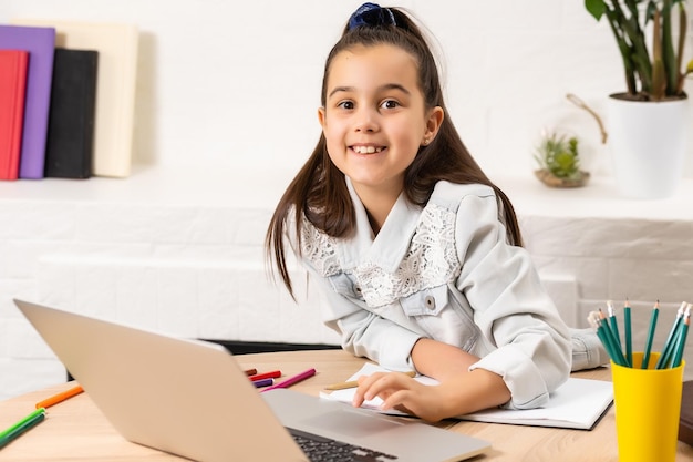 Student little school girl homework on laptop computer silver background