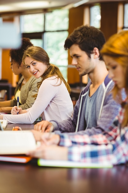 Studente che guarda l'obbiettivo mentre studiava con i compagni di classe